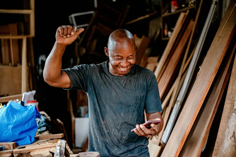 Un artisan content regarde son téléphone dans son atelier