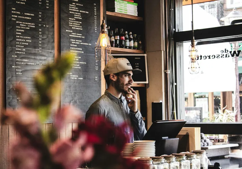 Un propriétaire de café au téléphone derrière son comptoir